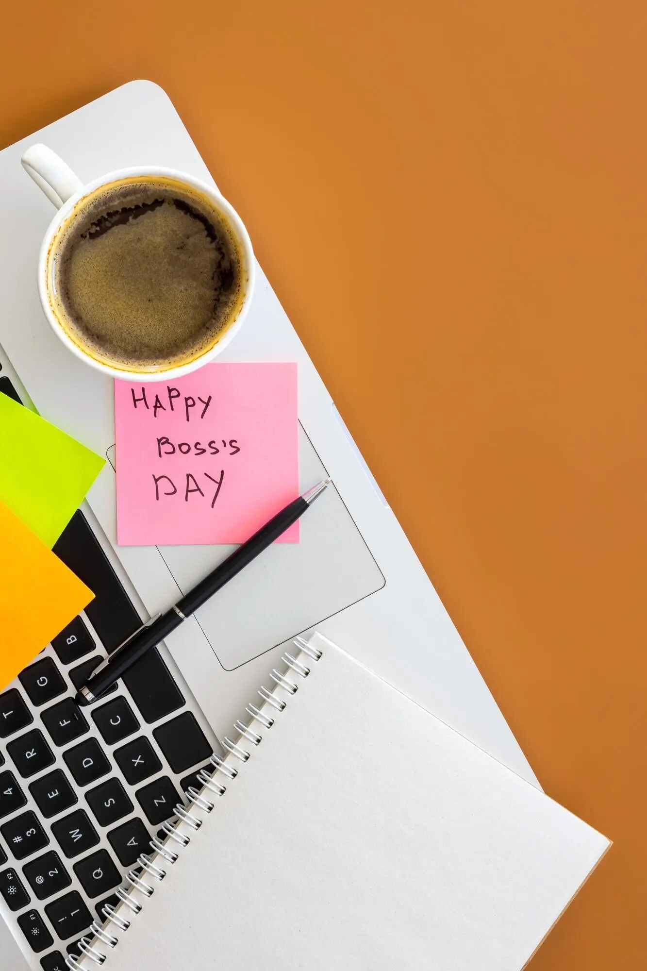 Konzept zum Tag des Chefs: Laptop und eine Tasse Kaffee als Flatlay auf einem Tisch.