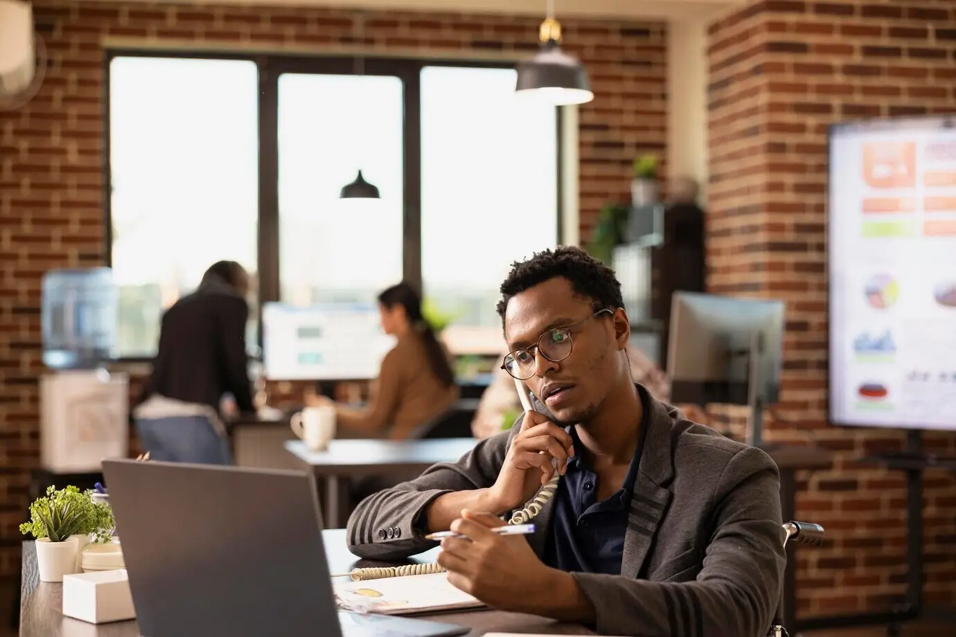 Schwarzer männlicher Angestellter, der ein Festnetztelefon verwendet.